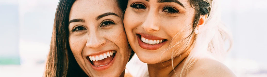 Close Up on Two Women Posing Personally and Smiling Showing off Crowns