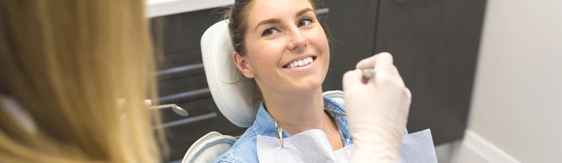 Woman Smiling in Dentist Chair Receiving a Dental Checkup